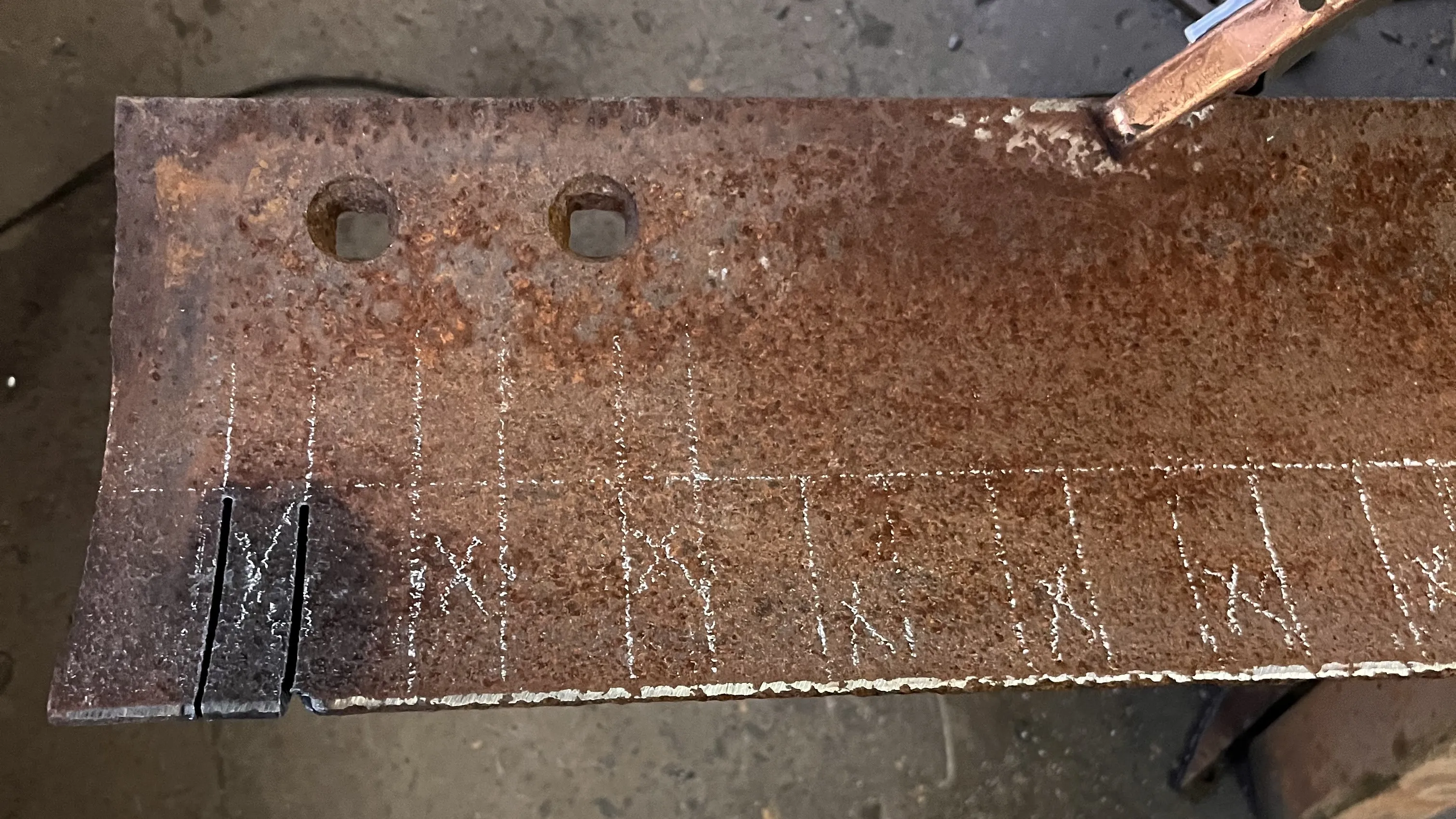 An image of a grader blade with markings being prepared for cutting out notches.